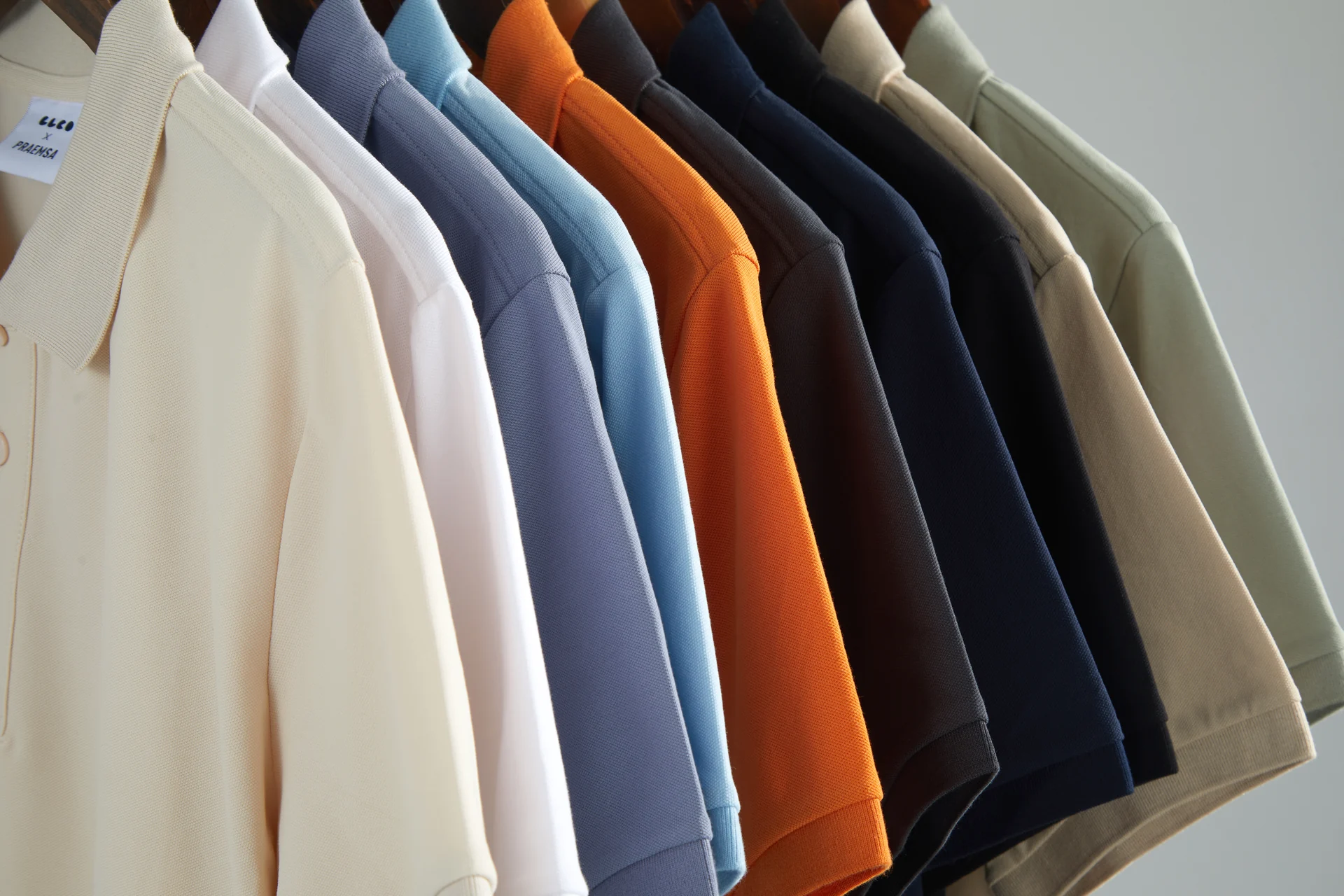 Product still-life photography for PRAEMSA polo shirts, led by the sage colourway, covering collar detail, stacked colourways, and rail displays.